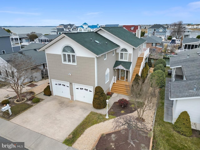 view of front of home featuring concrete driveway, roof with shingles, an attached garage, and a residential view