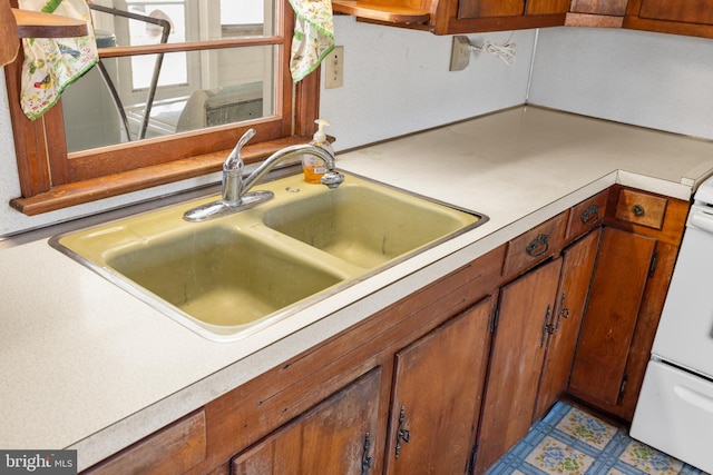 kitchen featuring brown cabinetry, light countertops, and a sink