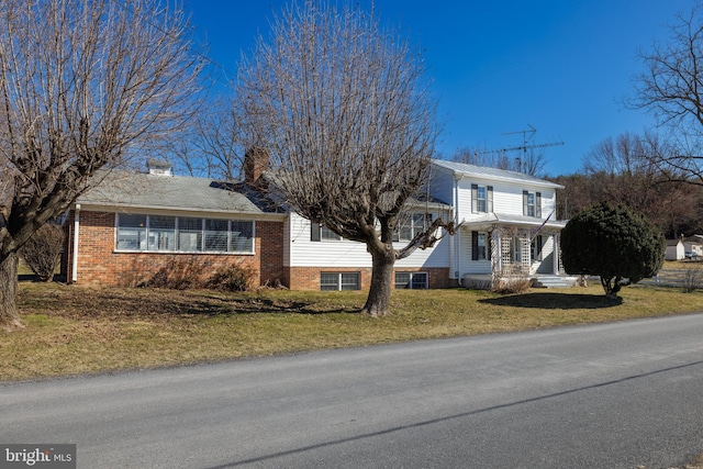 traditional-style home with brick siding, a chimney, and a front lawn