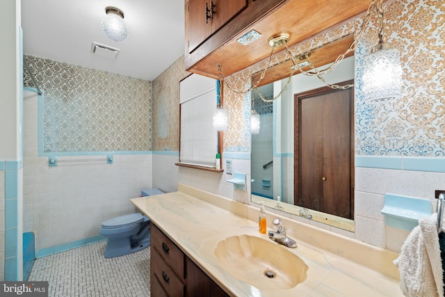 full bathroom with a wainscoted wall, tile walls, wallpapered walls, toilet, and walk in shower