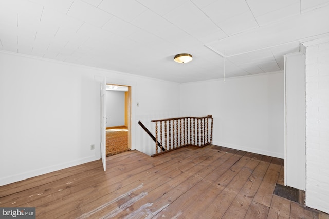 unfurnished room with wood-type flooring, ornamental molding, and baseboards