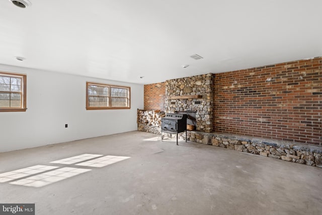 unfurnished living room featuring a wood stove, plenty of natural light, and visible vents