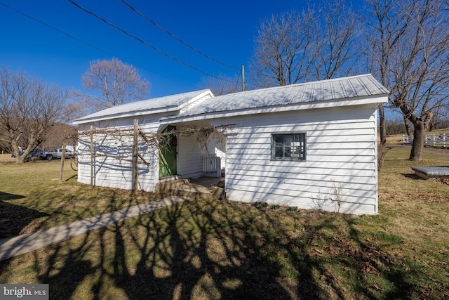 exterior space with metal roof and a yard