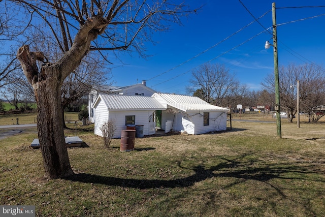 view of property exterior with metal roof, an outdoor structure, and a lawn