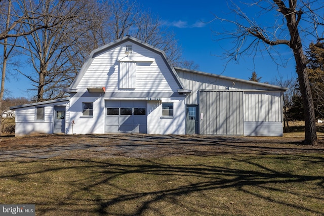 exterior space featuring driveway, a barn, a lawn, a gambrel roof, and an outdoor structure