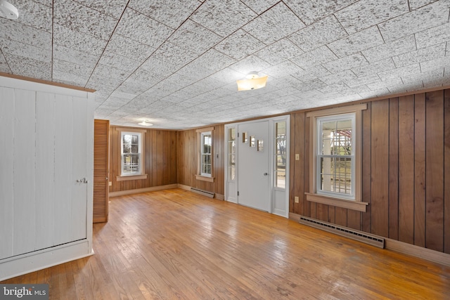 foyer featuring a baseboard heating unit, a baseboard radiator, a healthy amount of sunlight, and hardwood / wood-style flooring