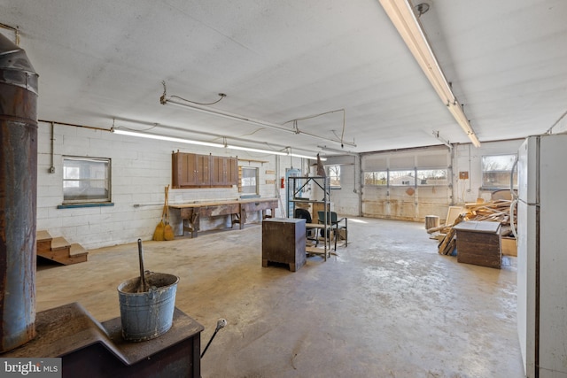 interior space with concrete block wall, a garage, and freestanding refrigerator