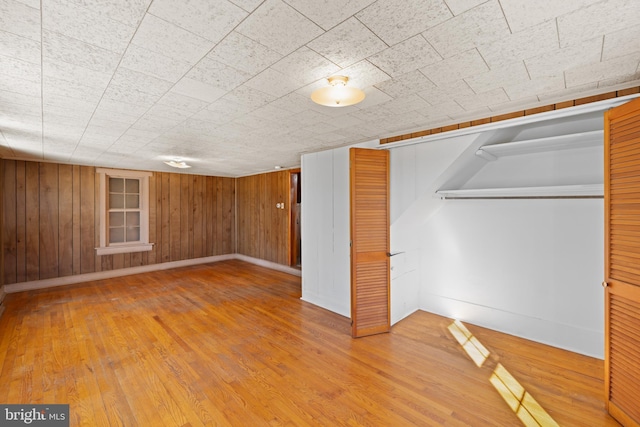 below grade area with wood walls, baseboards, and wood finished floors