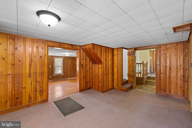 additional living space featuring a baseboard radiator, visible vents, wooden walls, and carpet