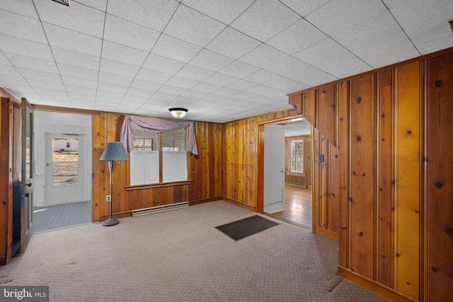 interior space with baseboards, baseboard heating, and wooden walls