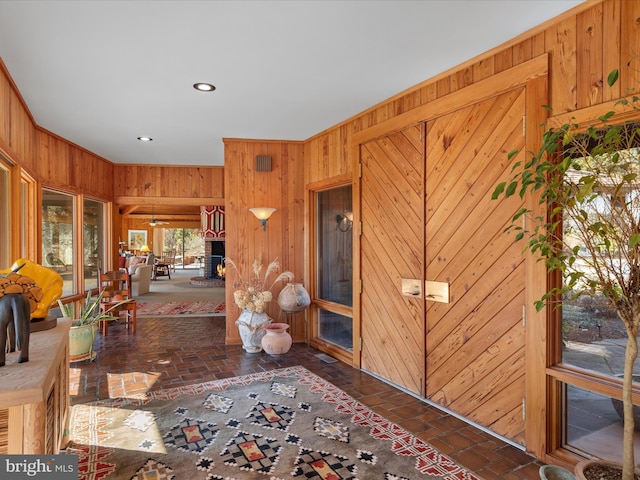 interior space with wooden walls, recessed lighting, and brick floor