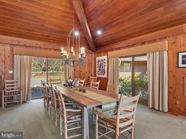 carpeted dining area featuring a notable chandelier, wood ceiling, wooden walls, and a healthy amount of sunlight