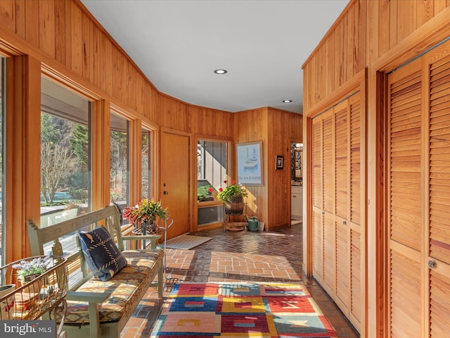 corridor featuring brick floor, wood walls, and recessed lighting