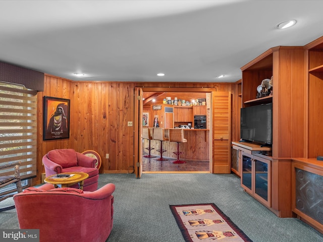 carpeted living room with a bar, wooden walls, and recessed lighting