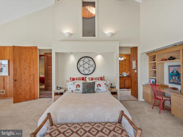 carpeted bedroom with visible vents, high vaulted ceiling, and wooden walls