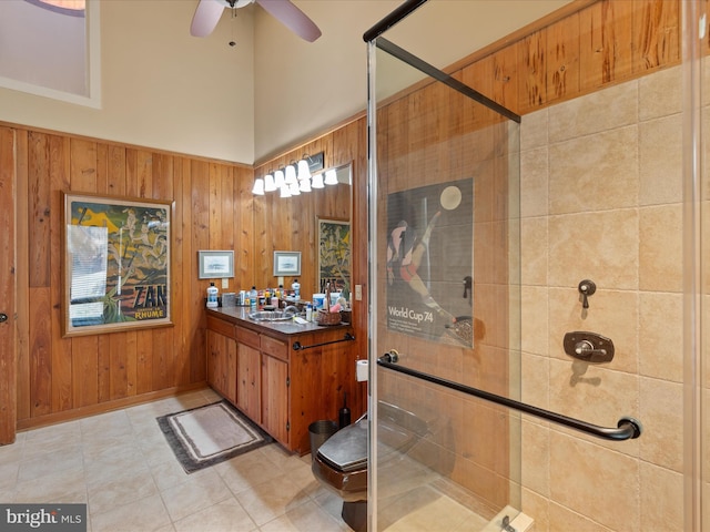 bathroom featuring a ceiling fan, vanity, wood walls, and a shower stall