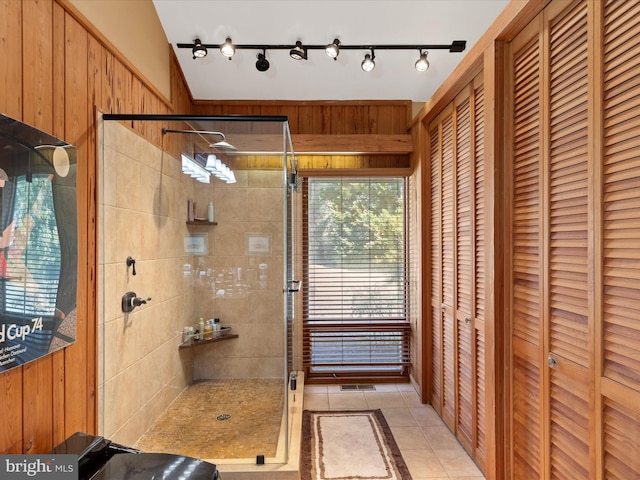 full bathroom with tile patterned floors, wooden walls, a stall shower, and a closet