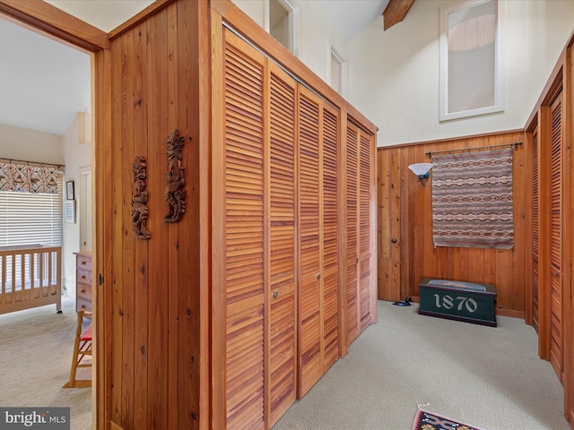 hall featuring carpet flooring and wood walls