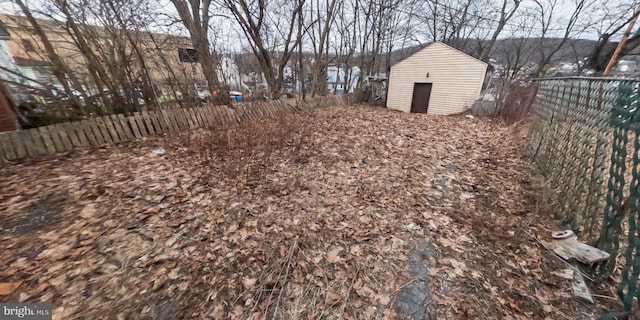 view of yard featuring a storage shed, a fenced backyard, and an outbuilding