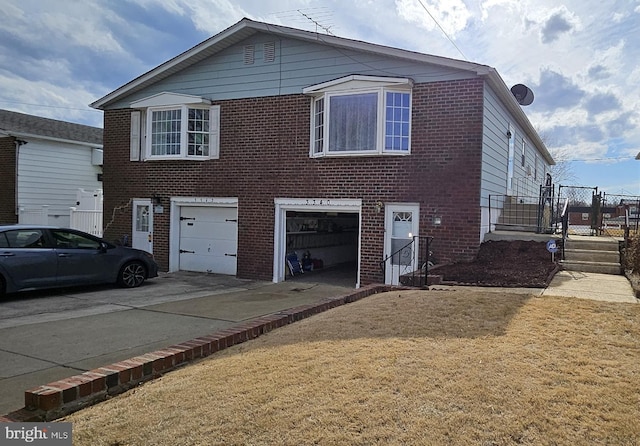 view of front of property featuring a garage, brick siding, driveway, and fence