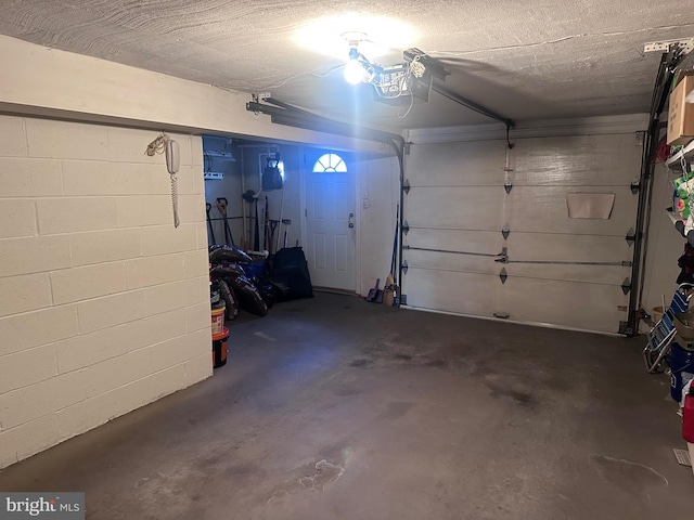 garage featuring concrete block wall and a garage door opener