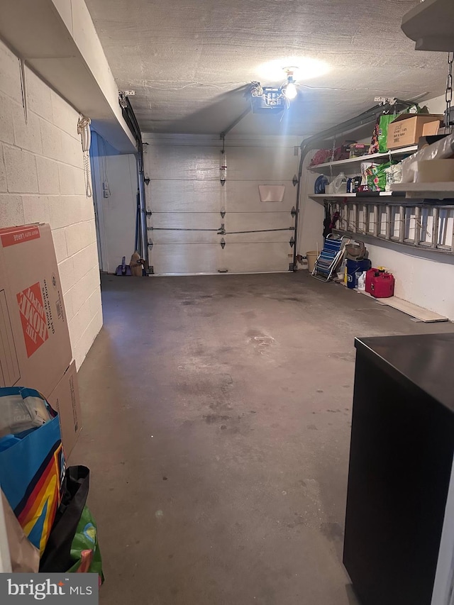 garage with a garage door opener and concrete block wall