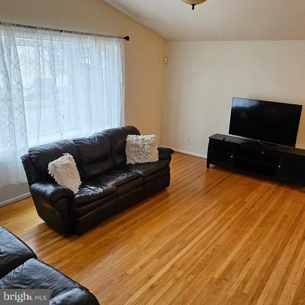 living room with vaulted ceiling and light wood-type flooring