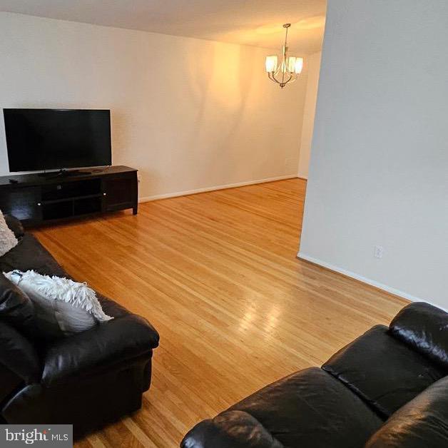 living room featuring a notable chandelier, baseboards, and wood finished floors