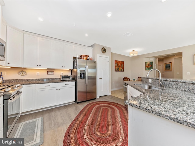 kitchen featuring a sink, stainless steel appliances, light wood-type flooring, and white cabinetry