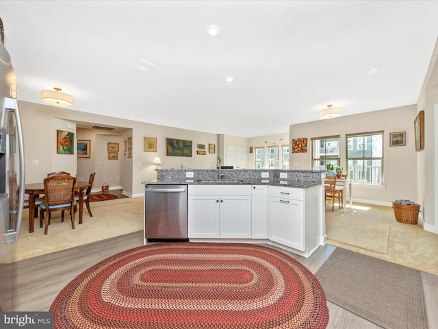 kitchen with stone counters, light wood-style flooring, a sink, white cabinets, and dishwasher