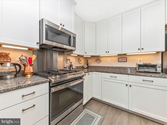 kitchen with white cabinets, a toaster, light wood-style floors, and stainless steel appliances