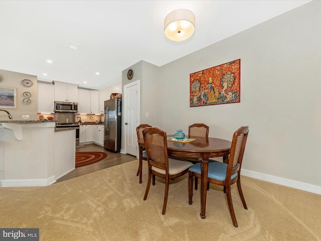 dining room featuring recessed lighting, light colored carpet, and baseboards