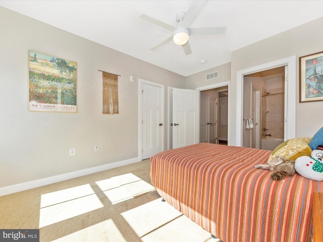 carpeted bedroom featuring visible vents, a ceiling fan, ensuite bathroom, and baseboards