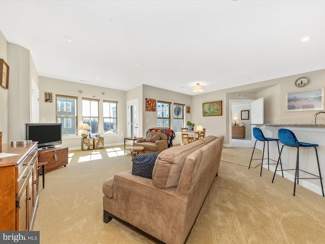 living area with visible vents, light carpet, and baseboards