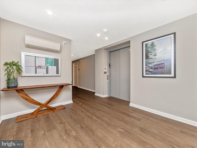 entrance foyer with a wall unit AC, elevator, wood finished floors, and baseboards