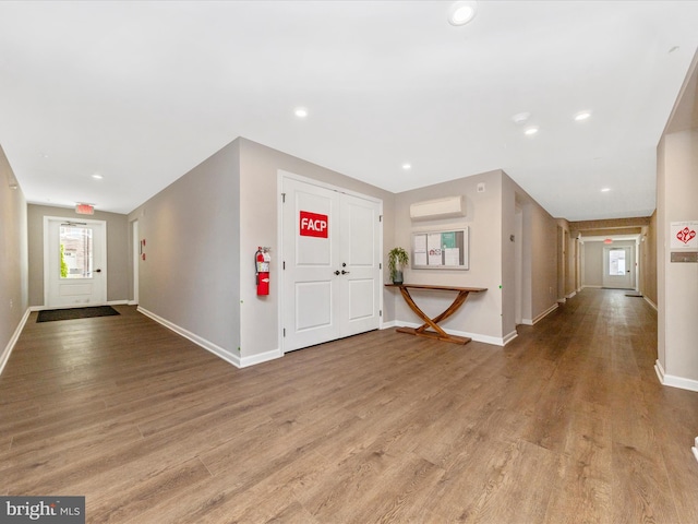 entryway with recessed lighting, an AC wall unit, baseboards, and wood finished floors