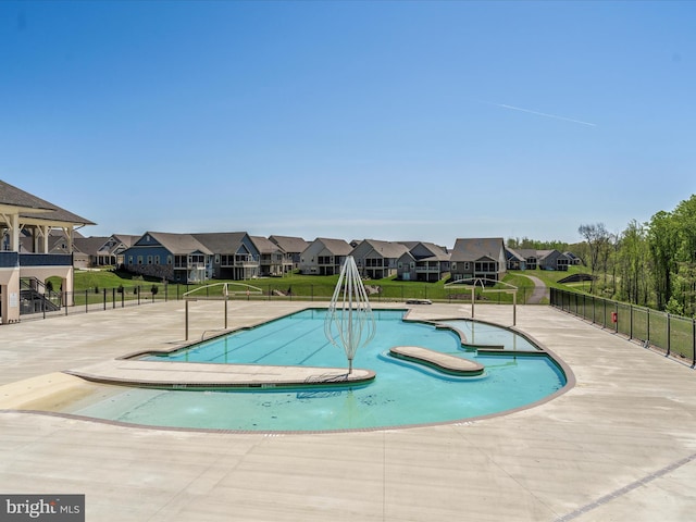 pool with fence, a residential view, and a lawn