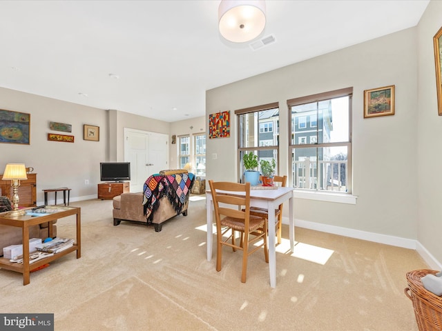 carpeted dining space with baseboards and visible vents