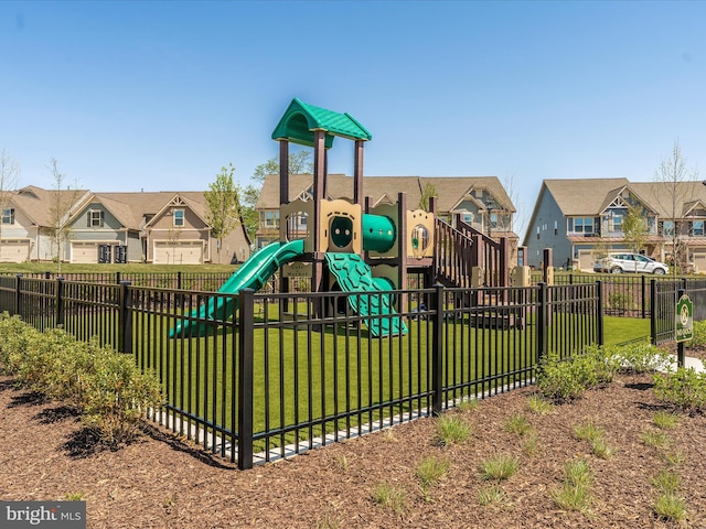 community play area with fence, a lawn, and a residential view