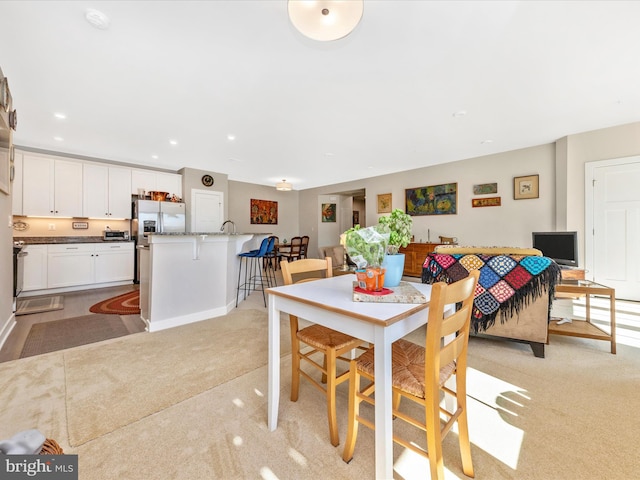 dining space featuring recessed lighting and light colored carpet