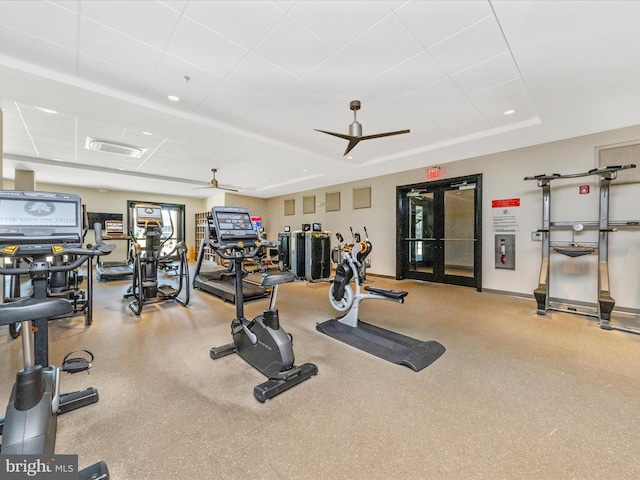 workout area featuring a raised ceiling and ceiling fan