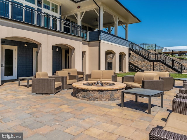 view of patio / terrace with an outdoor living space with a fire pit, stairs, and a balcony