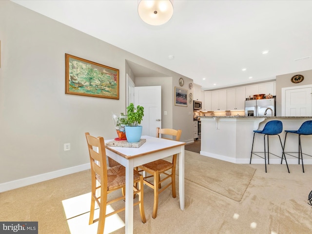 dining area with recessed lighting, light colored carpet, and baseboards