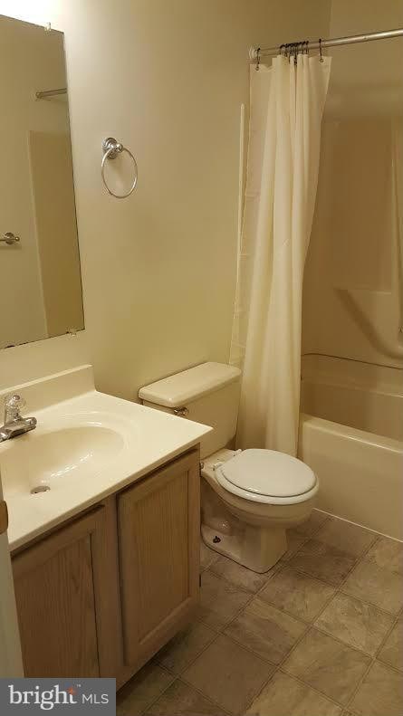 bathroom with toilet, shower / bath combination with curtain, and vanity