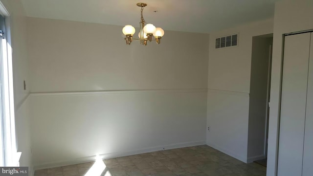 spare room with tile patterned floors, visible vents, baseboards, and an inviting chandelier