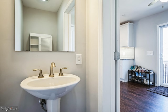 bathroom with ceiling fan, wood finished floors, a sink, and decorative backsplash