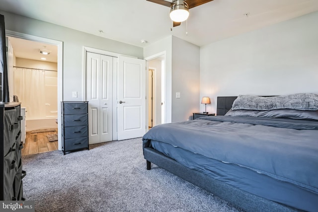 carpeted bedroom featuring a closet, ceiling fan, and ensuite bath