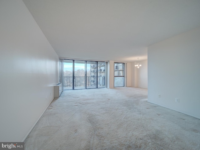 carpeted empty room featuring floor to ceiling windows and a notable chandelier