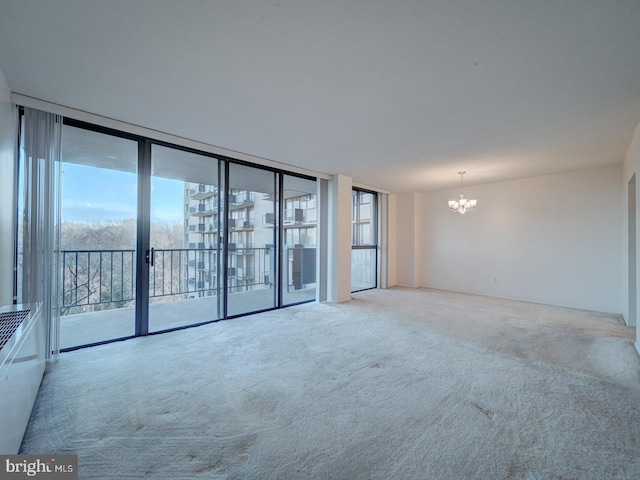 unfurnished room featuring carpet, an inviting chandelier, and floor to ceiling windows