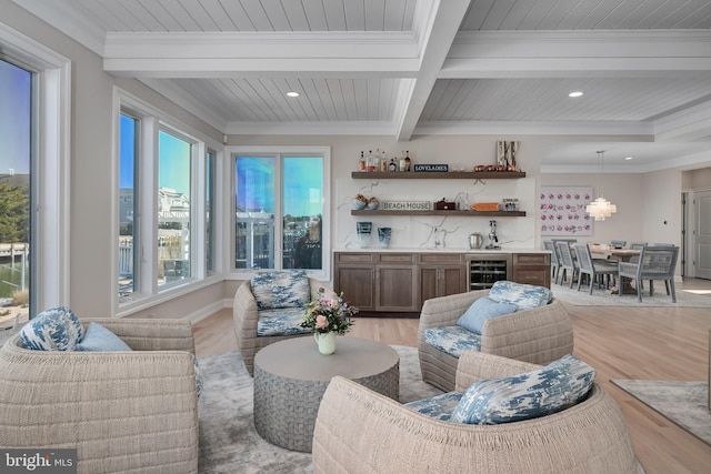 living room featuring light wood-style floors, beam ceiling, indoor wet bar, and crown molding